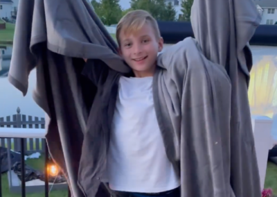 kid standing outside with blanket wrapped around him