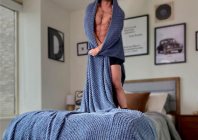 guy standing on bed with blanket wrapped around him